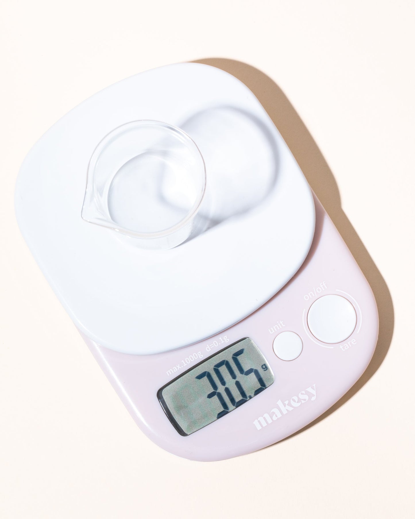 Digital cosmetic scale with a white display and brown base on a white background