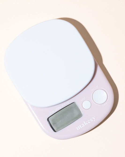 Pink digital cosmetic scale with a white screen on a light beige background