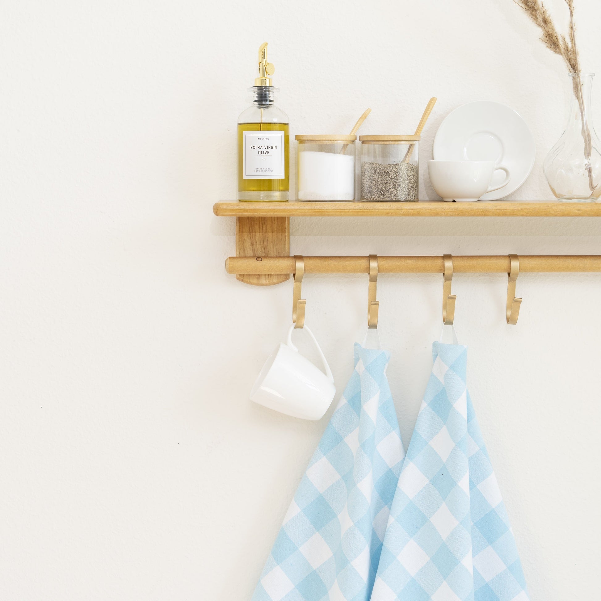 Wooden shelf with hooks, a mug, and checkered towels in a kitchen setting.