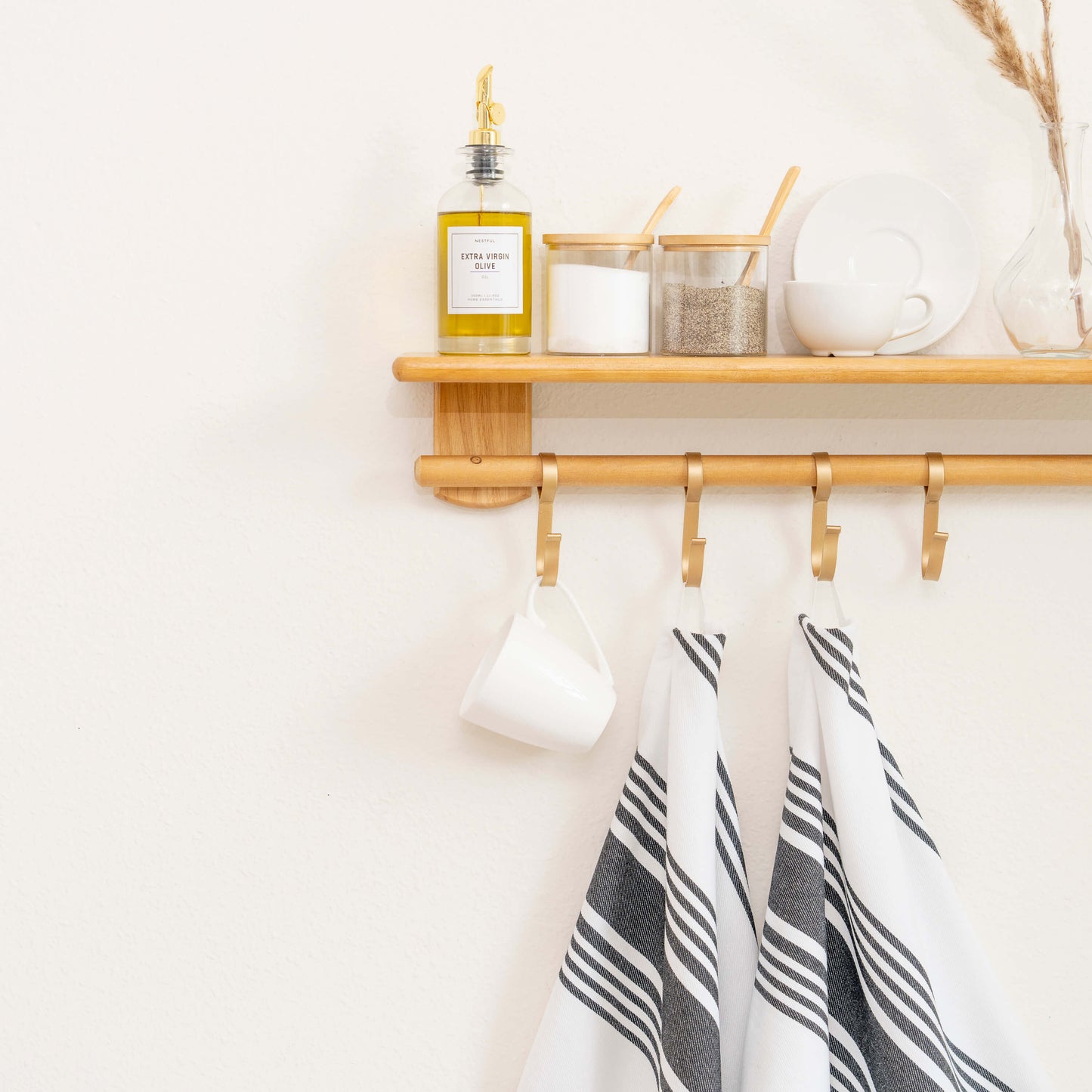 Wooden shelf with hooks, a bottle, and decorative items against a white wall.