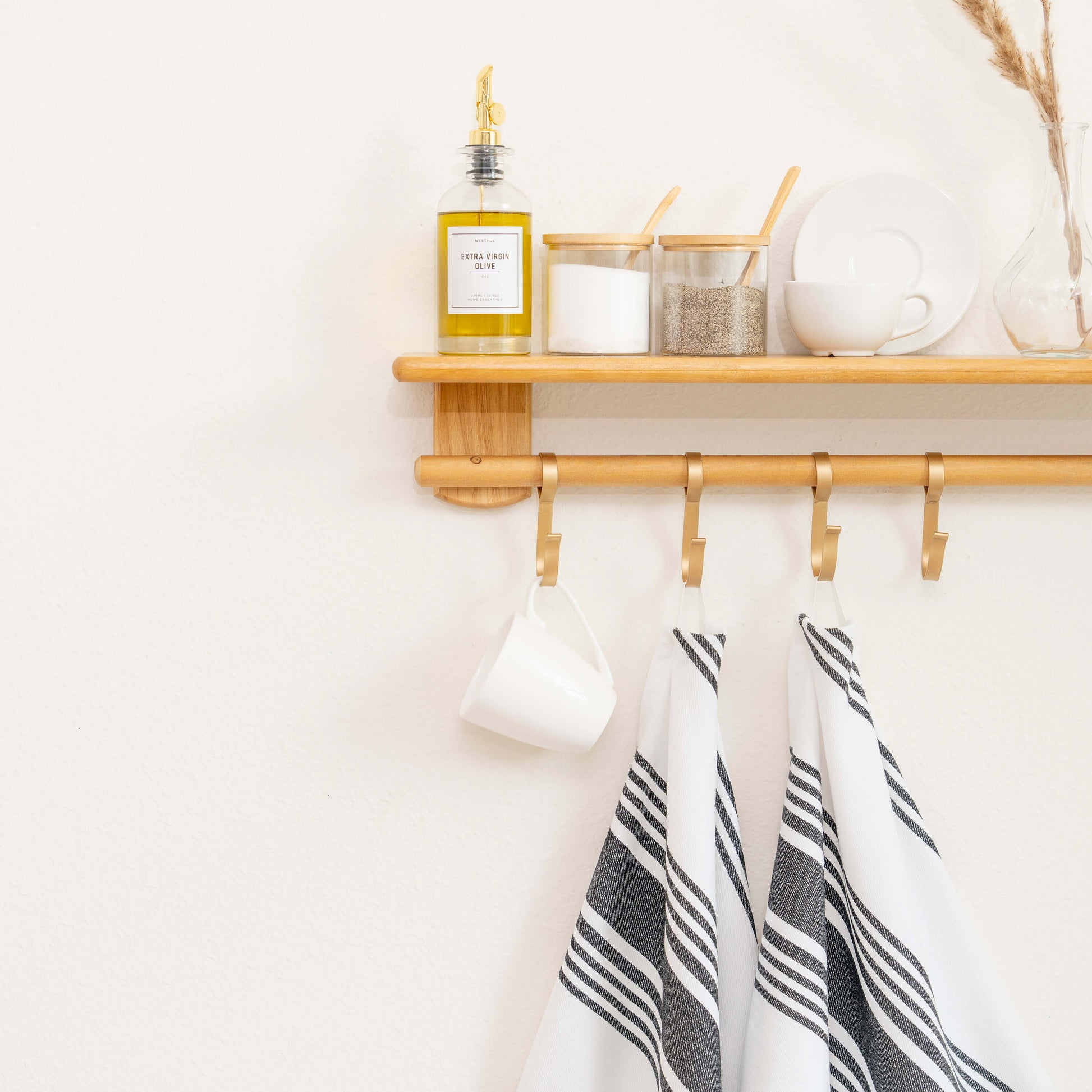 Wooden shelf with hooks, a bottle, and decorative items against a white wall.