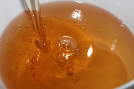 Hazelnut oil being dripped into a white bowl 