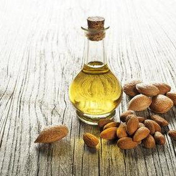 Bottle of almond oil with almonds on a wooden surface