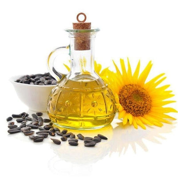 Glass bottle of sunflower oil with sunflower seeds and a sunflower on a white background