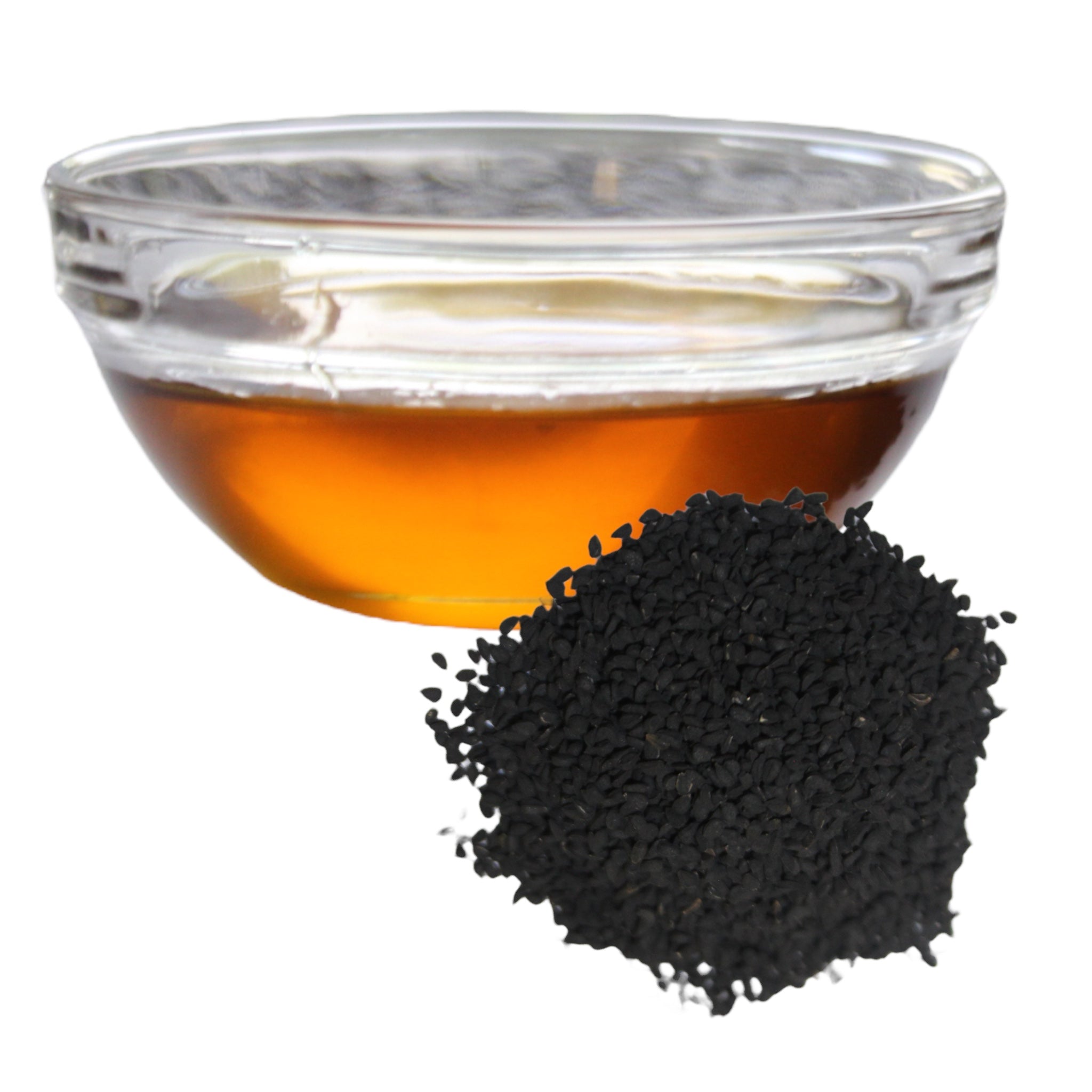Clear glass bowl with black cumin seed oil next to a pile of black cumin seeds on a white background