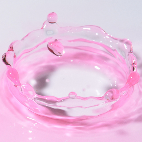 Pink PDRN liquid droplet creating ripples on a white background