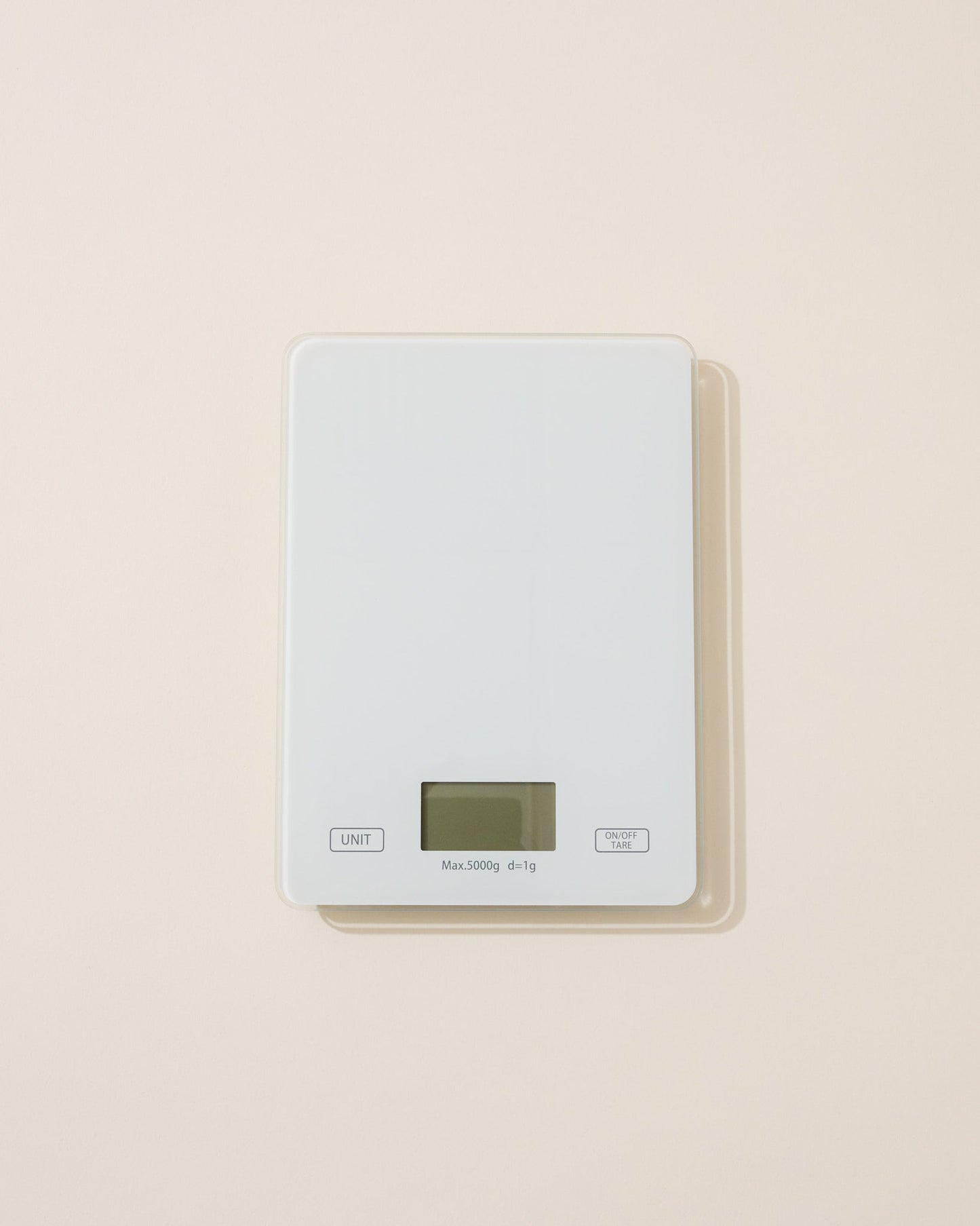 Digital cosmetic scale with a light gray top and beige base on a beige background
