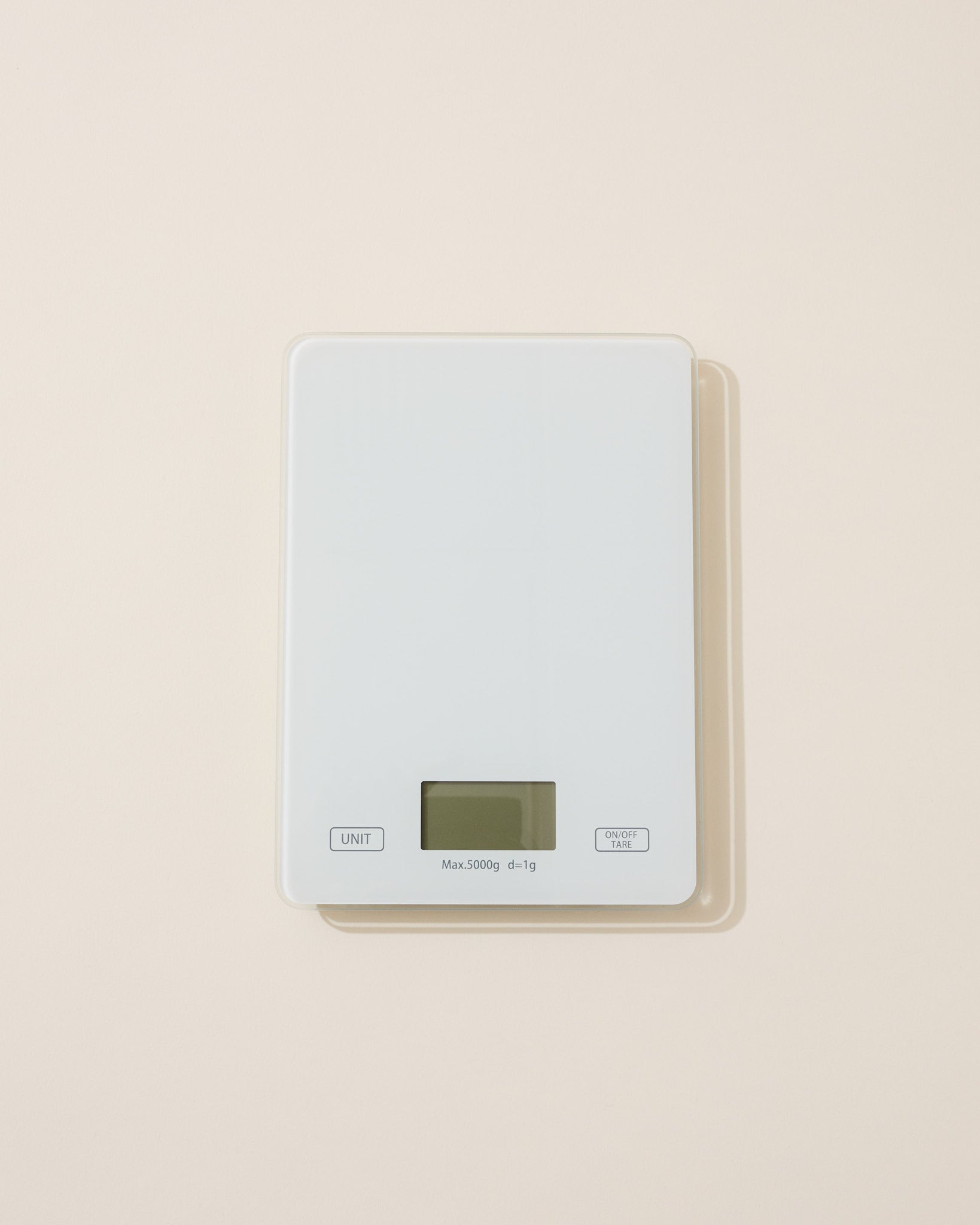 Digital cosmetic scale with a light gray top and beige base on a beige background