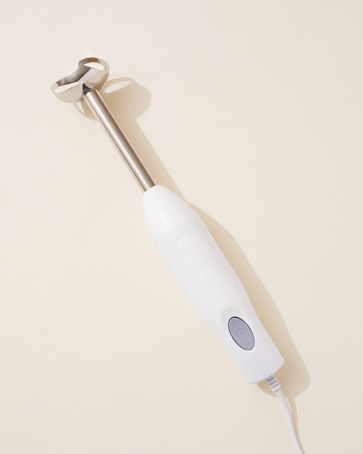White handheld blender on a beige background