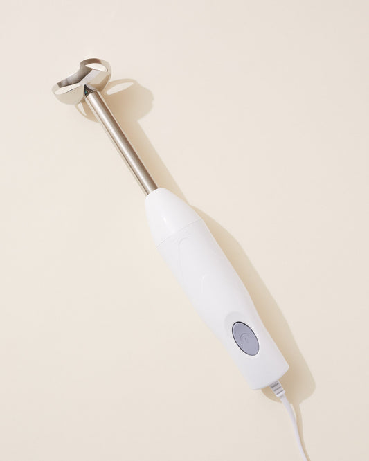 White handheld blender on a beige background